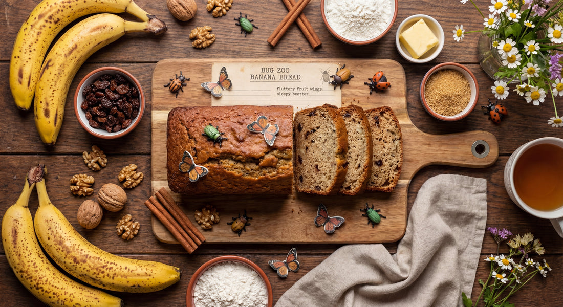 Overhead banana bread loaf and slices on a cutting board with bananas, walnuts, cinnamon, and butterfly and beetle decorations.