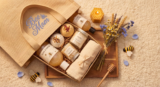 Open wooden “Bee Mom” spa gift box with bath products, honeycomb candle, dried flowers, and bee accents on a beige towel.
